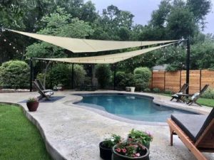 Two tan triangular shade sails providing shade to the pool